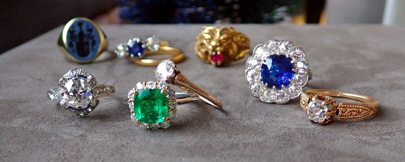 Rings in a beige fabric display case, featuring a variety of gemstones and diamonds