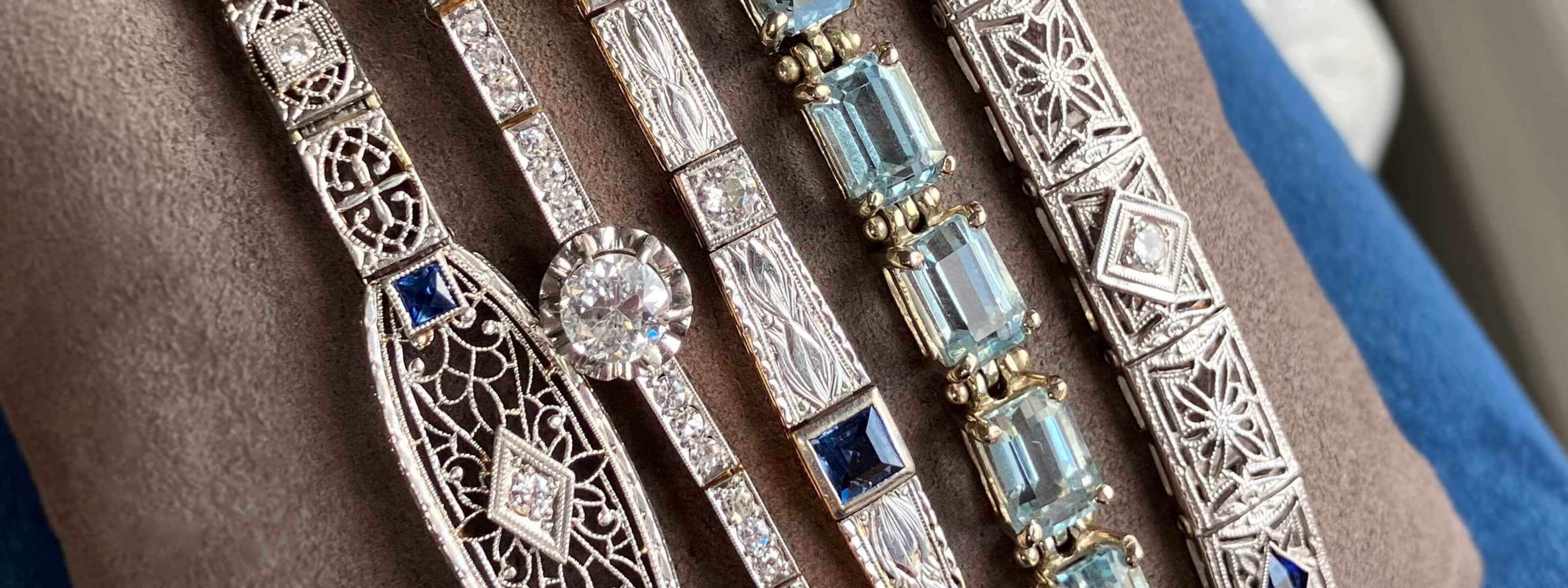 A variety of vintage bracelets laid out on a grey fabric display