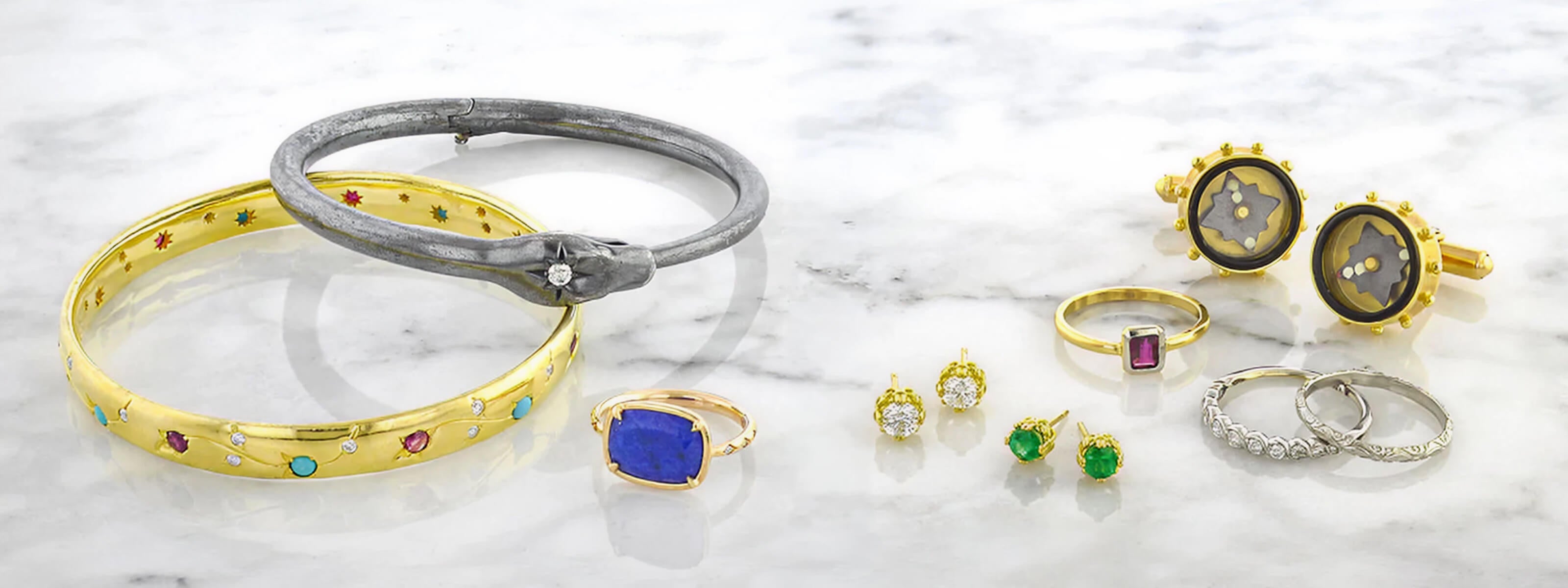 Collection of Heirloom by Doyle & Doyle jewelry laying on a marble surface