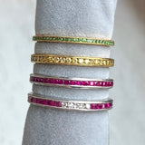 Four gemstone eternity band rings in tsavorite green garnet, yellow diamond, and ruby, all from Doyle & Doyle vintage and antique jewelry boutique